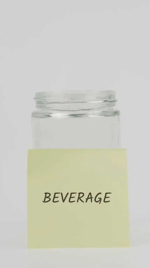 Beverage text or word on yellow sticky note attached to glass jar with hand Stock Footage 311681377