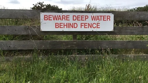 Beware Deep Water sign attached to fence Stock Footage 77470128
