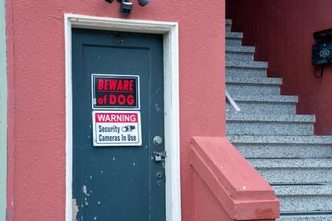 Beware of dog and security camera warning sign in front of locked house Stock Photos