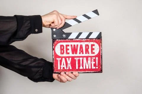 Beware Tax Time Warning Sign on Film Clapper Board Held in Hands Foto stock