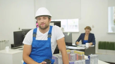 Bewildered builder with coffee talks on camera with smile Stock Footage 121812083