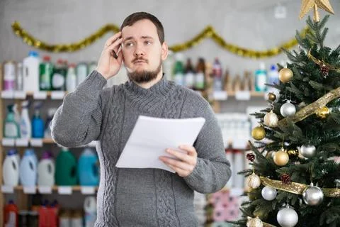 Bewildered man merchandiser work with document, draws up plan for purchasing 库存照片