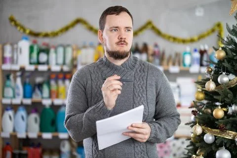 Bewildered man merchandiser work with document, draws up plan for purchasing 库存照片