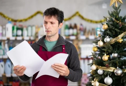 Bewildered man seller work with document, looks at report and is upset by Stock Photos