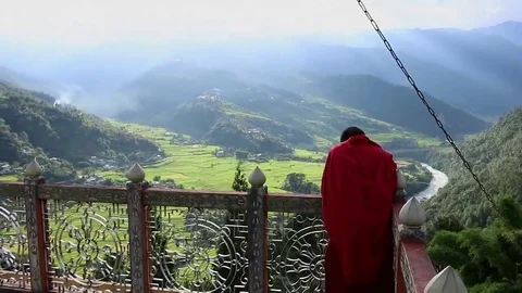 Bhutan monk on top of a monastery with view over Punakha area Stock Footage 69085049