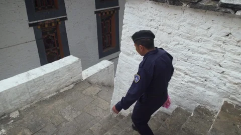 A Bhutanese security guard walking inside an old monastery in Punakha Video stock 104957872