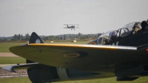 A bi plane lands with a Spitfire in the foreground in slow motion Stock Footage 115054579