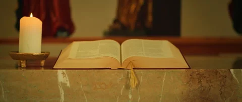 Bible and candle placed on a marble altar during service inside catholic church Stock Footage 313705188