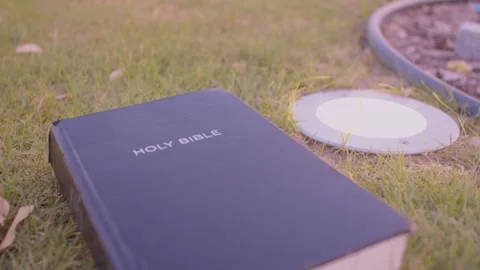 Bible down on ground in the park with an uplight besides Stock Footage 285648419