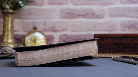 Bible falling for communion and study on gray table with glasses and clock Stock Footage 310604568