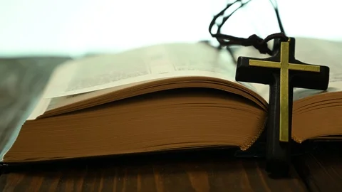 Bible lies open on a table with a cross Stock Footage 125502136