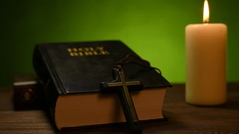 Bible is lying on a table and a candle is burning Stock Footage 125502748