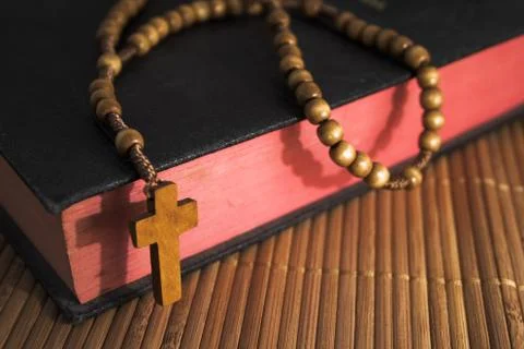 Bible with rosaries-beads crucifix on a straw table Stock Photos