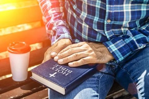 Bible study. Young man reading the Bible in the park. Christian faith concept. Stock Photos