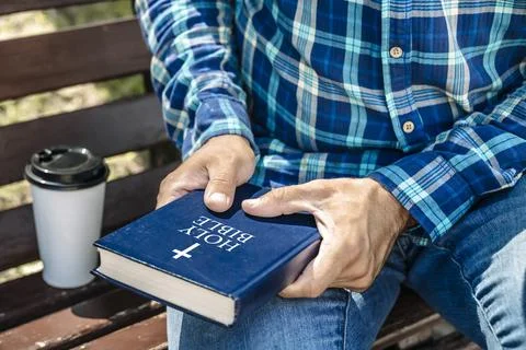 Bible study. Young man reading the Bible in the park. Christian faith concept. Stock Photos