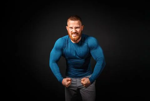 Biceps pumping. An aggressive man with an effort shows his biceps. Black back Stock Photos