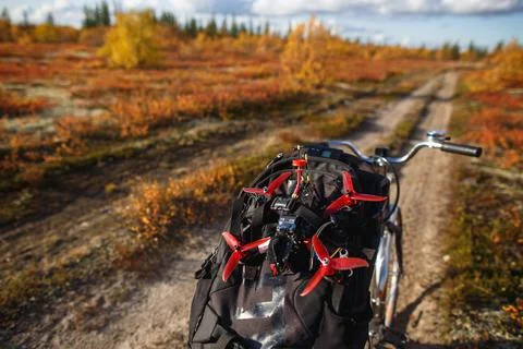 Bicycle with backpack and custom drone on the tundra road. Touring kit for Stock Photos