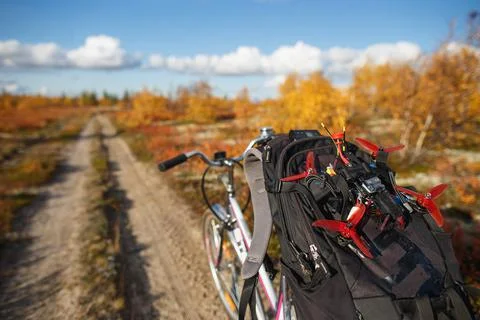 Bicycle with backpack and custom drone on the tundra road. Touring kit for Stock Photos