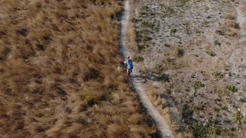 A bicycle cyclist rides through the park among dry grass. The concept of solo Stock Footage 116027884