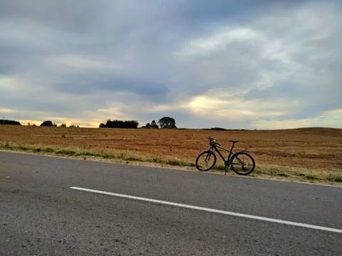 Bicycle on empty road in dry fields. travel alone. Stock Photos