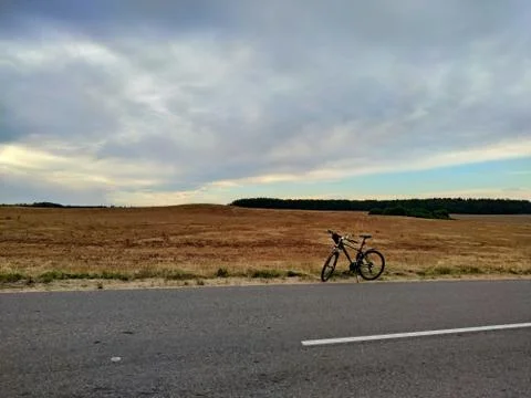 Bicycle on empty road in dry fields. travel alone. Stock Photos