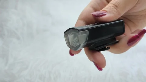 Bicycle flashlight in a womans hand close-up. A woman turns on and off a bicycle Stock Footage 318131109