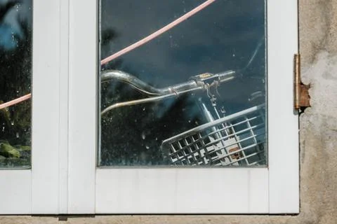 Bicycle handlebars and front basket visible behind a glass window Stock-Fotos