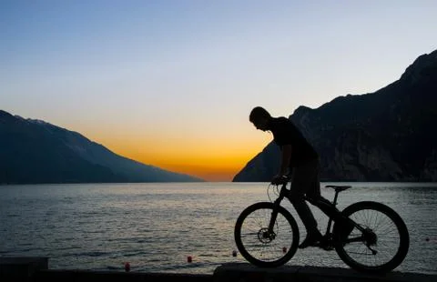 Bicycle on lake garda, red sunset background . Stock Photos