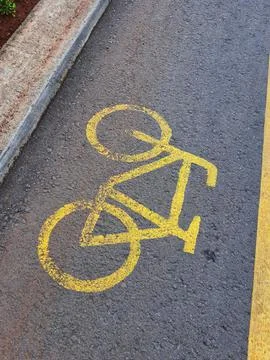 Bicycle lane sign in yellow with solid lines on asphalt road in Indonesia. Stock Photos