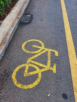 Bicycle lane sign in yellow with solid lines on asphalt road in Indonesia. Stock Photos