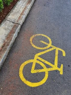 Bicycle lane sign in yellow with solid lines on asphalt road in Indonesia. Stock Photos