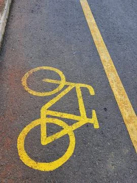 Bicycle lane sign in yellow with solid lines on asphalt road in Indonesia. Stock Photos