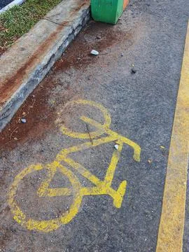 Bicycle lane sign in yellow with solid lines on asphalt road in Indonesia. Stock Photos