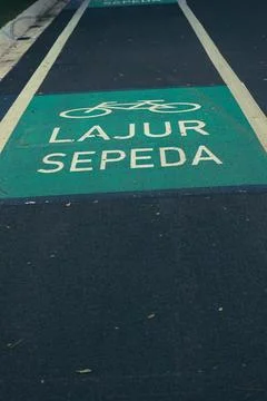Bicycle lane sign in yellow with solid lines on asphalt road in Indonesia Stock Photos