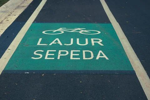 Bicycle lane sign in yellow with solid lines on asphalt road in Indonesia Stock Photos