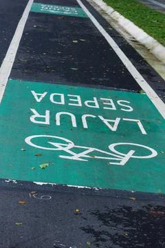 Bicycle lane sign in yellow with solid lines on asphalt road in Indonesia. Stock Photos