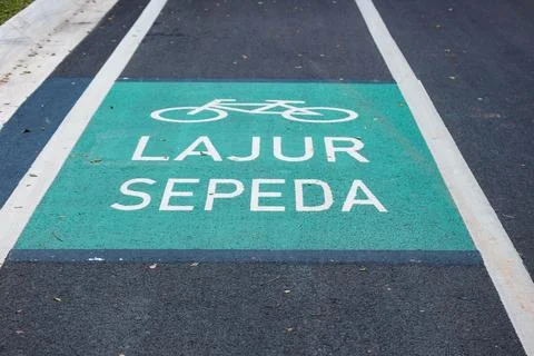Bicycle lane sign in yellow with solid lines on asphalt road in Indonesia. Stock Photos