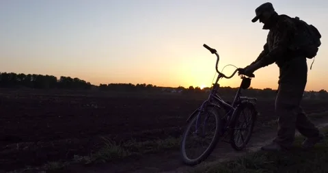 Bicycle. A man with a backpack gets on a Bicycle at sunset. Vídeos de archivo 130426783