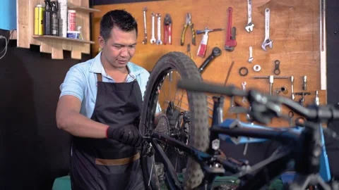 Bicycle mechanic in aprons installing wheels while fixing problems Stock Footage 163037089
