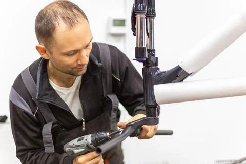 Bicycle mechanic assembling a bike frame with suspension fork and crankset Stock Photos
