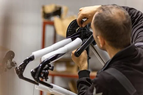 Bicycle mechanic assembling a bike frame with suspension fork and crankset Stock Photos