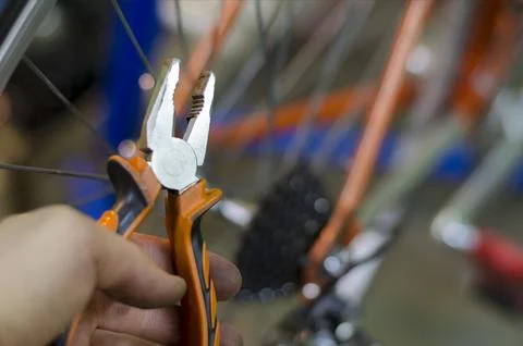 Bicycle mechanic in a workshop in the repair process, holds a tool in his han Stock-Fotos