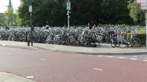 Bicycle park area next to cycle lanes with people riding past Stock Footage 169096983