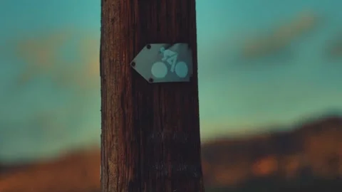 Bicycle path marking on a wooden pole against the background of a landscape Stock Footage 244704260