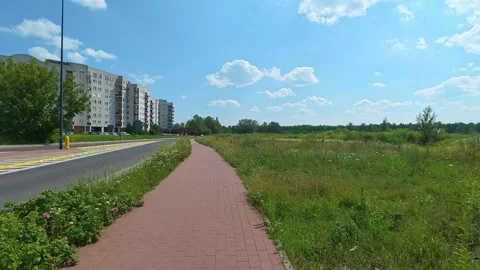 Bicycle path running past apartment blocks in suburban meadow Stock Footage 340360548