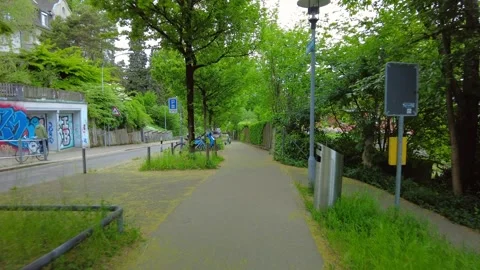 Bicycle path under green trees next to a graffiti wall in Zurich Stock Footage 334633479