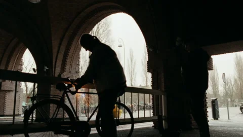 Bicycle thief silhouetted sawing through a bike lock Stock Footage 334779686