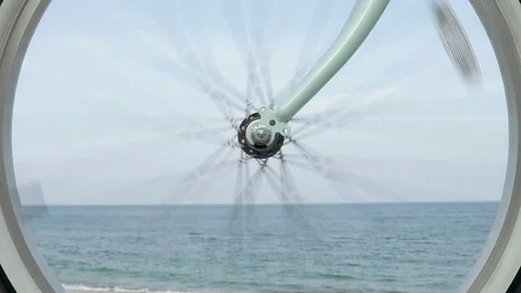 Bicycle wheel rotates against the backdrop of the sea and the beach in slow m Stockbeeldmateriaal 76702570