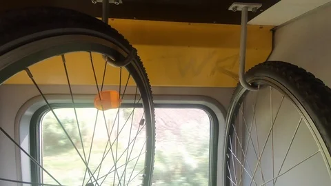 Bicycles hang on rack in moving train, green trees in window Stock Footage 114647388