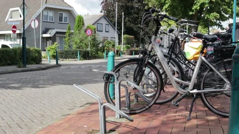Bicycles parked at the side of a road. Car and cyclist pass on street Stock Footage 169087091